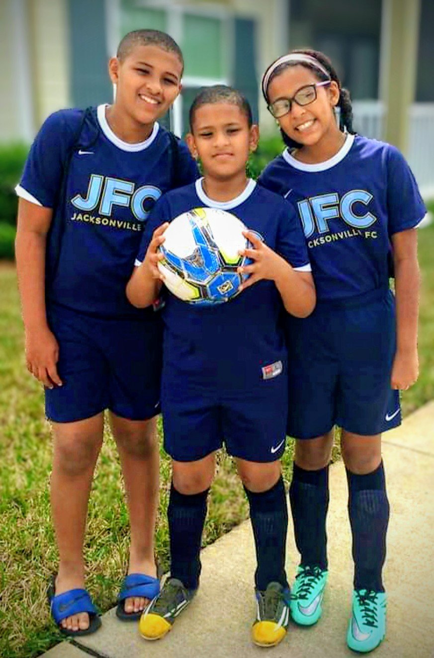 Three young players with a football, ready for training